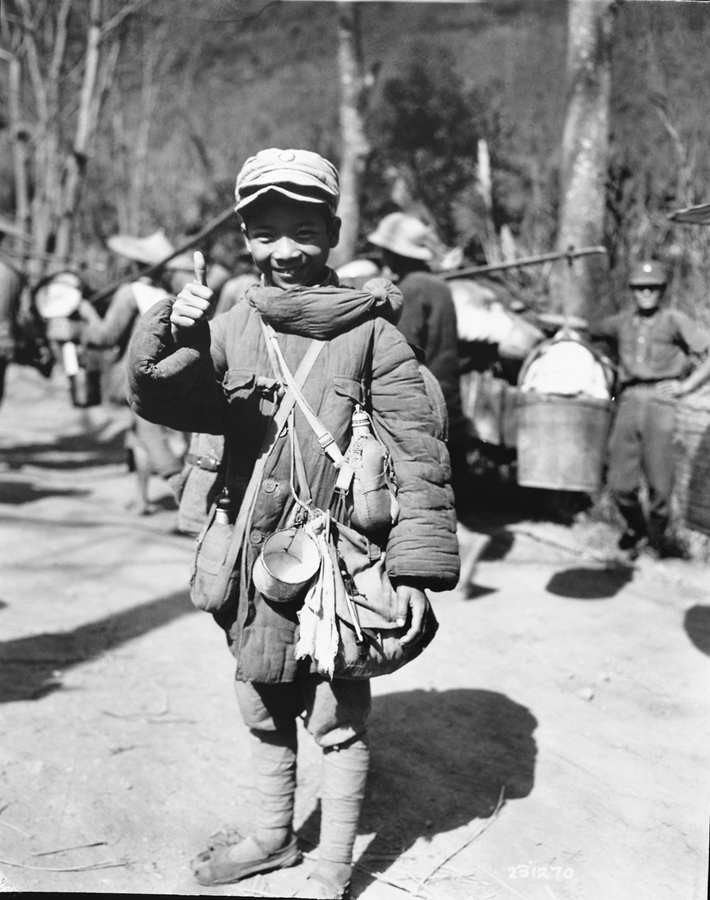 1944年12月5日，这一位重装在身的10岁中国军队士兵，隶属于即将在缅北密支那机场登机空运回国的部队（译者注：中国驻印军新6军）。美军通信兵（U