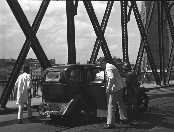 日本兵在外白渡桥搜查车辆。日本海军陆战队控制了在外滩横跨苏州河外白渡桥。他们截停和搜查所有进入虹口的汽车。若希望穿越过桥，必须经过日本海军总部允许。虹口是上海市的一个区。在桥的背景是百老汇大厦建筑。坐落在外滩英国控制的地区。1937年。